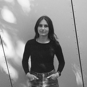 A black-and-white shot of a woman against a sun-dappled background.